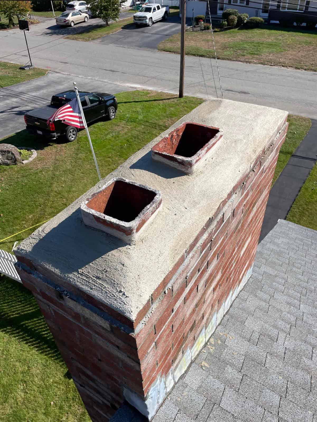 Brick chimney with two exposed terracotta flues on top.
